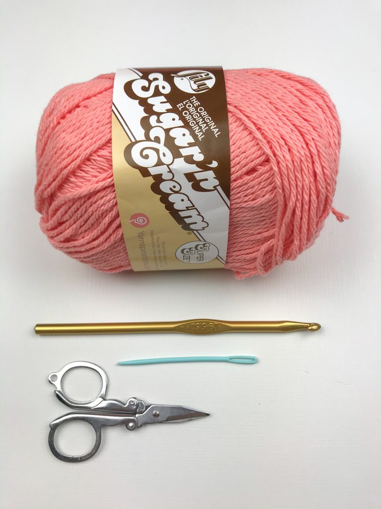 Supplies needed to complete a crochet dishcloth: yarn, hook, yarn needle and scissors.